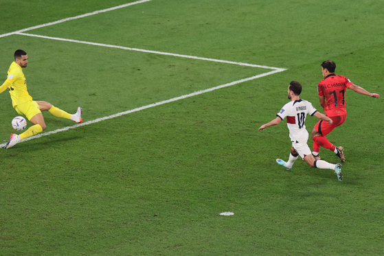 Hwang Hee-chan, right, scores Korea's second goal in injury time on Friday during the match between Korea and Portugal at the Education City Stadium in Al-Rayyan, west of Doha. Hwang's second goal eventually became the winning goal as Korea won the match 2-1 and qualified for the round of 16. [AFP/YONHAP]