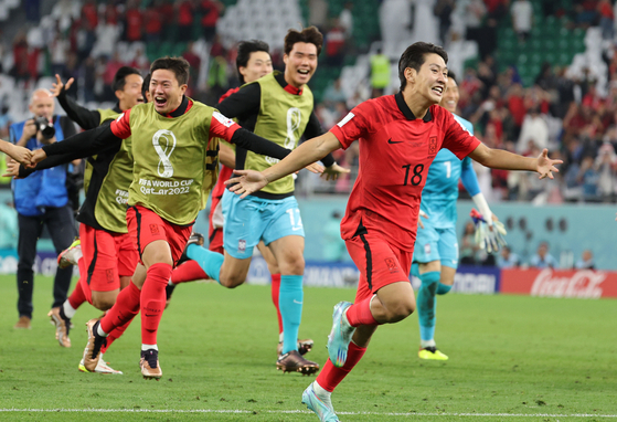 Lee Kang-in, right, celebrate with his teammates after beating Portugal 2-1 and qualifying for the knockout stages of the 2022 World Cup on Friday evening at the Education City Stadium in Al-Rayyan, west of Doha. After conceding a goal five minutes into the match, Kim Young-gwon scored the equalizer in the 27th minute and Hwang Hee-chan scored the winner in the 91st minute. [AFP/YONHAP]