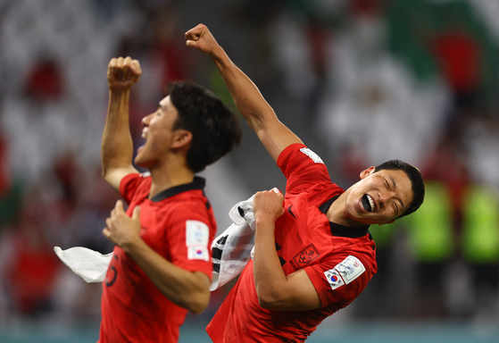 Hwang Hee-chan, right and Hwang In-beom celebrate after beating Portugal 2-1 and qualifying for the knockout stages on Friday evening. Hwang Hee-chan scored the winning goal in the 91st minute. [REUTERS/YONHAP]