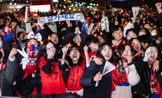 Crowds of people cheer after learning that the Taeguk Warriors advanced to the round of 16 for the first time in 12 years at the 2022 Qatar World Cup, at Gwanghwamun Square in central Seoul, early Saturday. Korea beat Portugal 2-1 Friday in the last Group H match, and Uruguay beat Ghana 2-0. [YONHAP]
