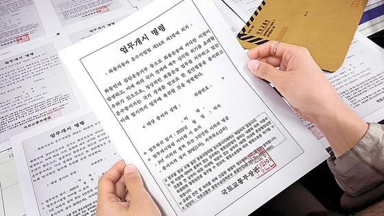 A government official holds up a printed copy of the executive order issued by President Yoon Suk-yeol for striking truckers to return to work at the Sejong government complex on Nov. 29. [YONAHP]