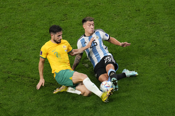 Argentina's Lisandro Martinez, right, vies for the ball with Australia's Mathew Leckie during the World Cup round of 16 match between Argentina and Australia at the Ahmad Bin Ali Stadium in Doha, Qatar, on Saturday. Argentina eventually won 2-1. [AP/YONHAP]