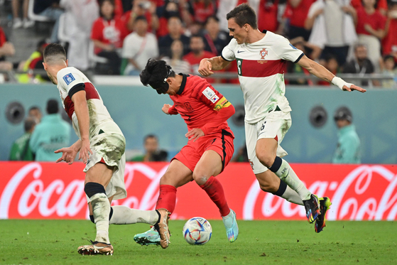 Son Heung-min, center, fights for the ball with Portugal's midfielder Joao Palhinha, right, during the Qatar 2022 World Cup Group H football match between Korea and Portugal at the Education City Stadium in Al-Rayyan, west of Doha, on Friday. [AFP/YONHAP]