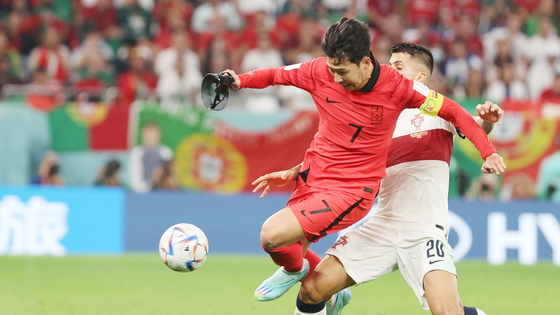 Son Heung-min vies for the ball in injury time without wearing his face mask during Korea's last group stage match against Portugal on Friday evening at the Education City Stadium in Al-Rayyan, west of Doha. Son is holding his protection mask in his hand instead of wearing it on his face. [NEWS1]