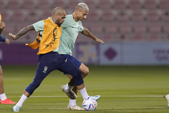 Brazil's Richarlison, right, and Dani Alves practice during a training session at the Grand Hamad stadium in Doha, Qatar on Sunday. Brazil will face Korea in a World Cup round of 16 match on Monday. [AP/YONHAP]