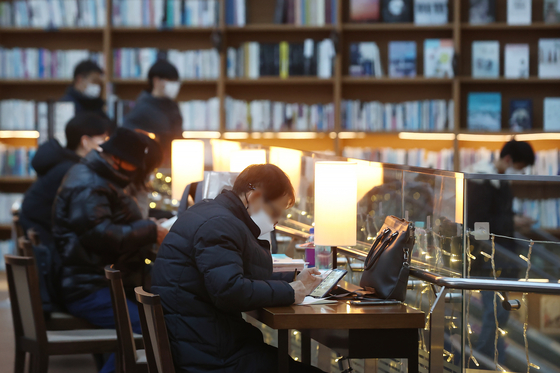 People wearing masks spend time at a bookstore in Seoul on Monday. [YONHAP]