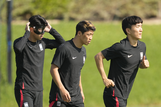 Son Heung-min, left, Hwang Hee-chan, center, and Hwang In-beom warm up during training on the eve of the World Cup round of 16 match between Brazil and Korea at the Al Egla Training Site 5 in Doha, Qatar, on Sunday. [AP/YONHAP]
