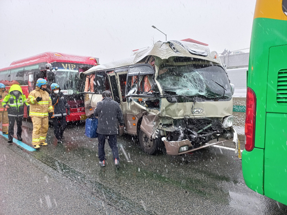 Police and fire fighters examine the scene of a collision between two large buses and a minibus on the Gyeongbu Expressway on Tuesday morning. [GYEONGGI DISASTER AND SAFETY HEADQUARTERS]