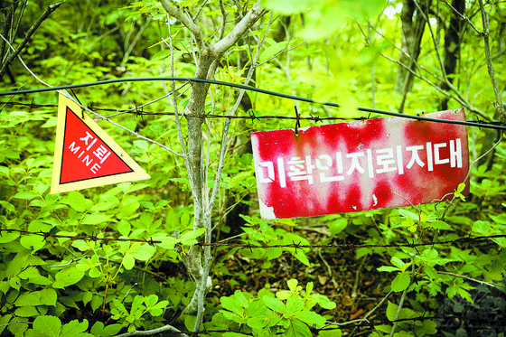 A file photo dated June 13, 2018, shows a warning sign before an area estimated to have land mines. [JOONGANG PHOTO]