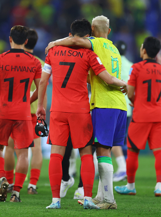 Le Brésilien Richarlison, à droite, console Son Heung-min après le match des huitièmes de finale entre le Brésil et la Corée lors de la Coupe du monde de football 2022 au stade 974 de Doha, au Qatar, lundi.  La Corée a été éliminée de la Coupe du monde et le Brésil s'est qualifié pour les quarts de finale. [REUTERS/YONHAP]
