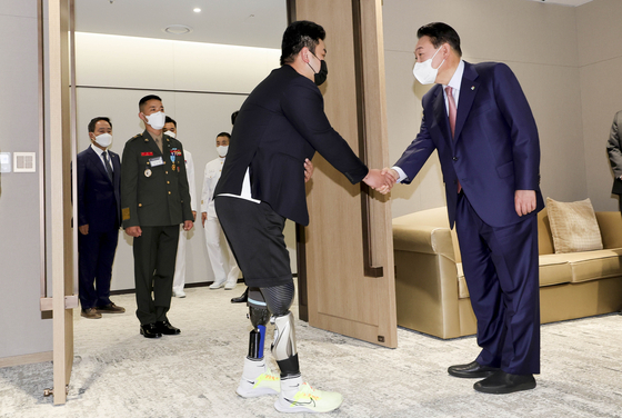 President Yoon Suk-yeol, right, shakes hands with Sgt. First Class Ha Jae-heon, left, who had lost his legs in a 2015 mine blast in the demilitarized zone in the inter-Korean border, at the Yongsan presidential office on June 9. [JOINT PRESS CORPS]