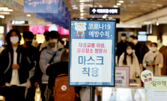 People wear masks at a book store in Seoul on Thursday as the indoor mask mandate is still in effect, as warned on the sign. [YONHAP]
