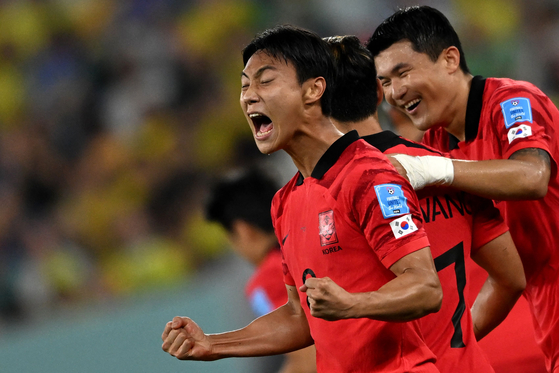 Paik Seung-ho, left, celebrates after scoring Korea's first goal during a round of 16 match between Brazil and Korea at Stadium 974 in Doha on Monday. [AFP/YONHAP]