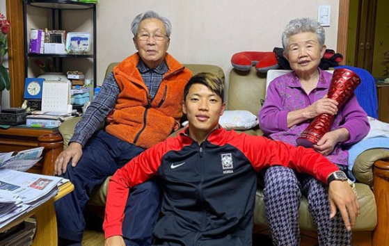 Hwang Hee-chan poses for a photo with his grandparents at their home on Wednesday. [SCREEN CAPTURE]