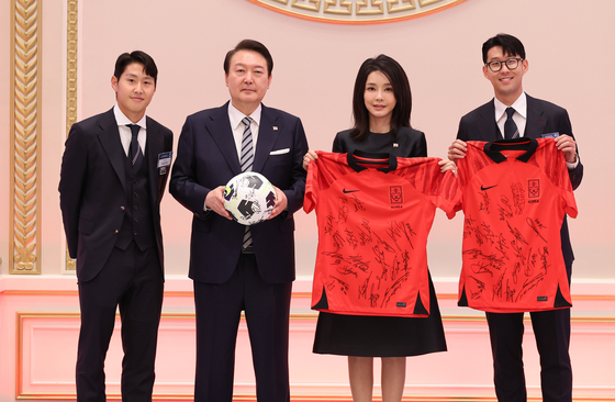 President Yoon Suk-yeol, second from left, and first lady Kim Keon-hee receive a football ball and signed uniforms from Son Heung-min, far right, and Lee Kang-in, far left, at a dinner banquet hosted for the Taeguk Warriors for their 2022 World Cup achievements at the Blue House guest house in central Seoul Thursday evening. [PRESIDENTIAL OFFICE]