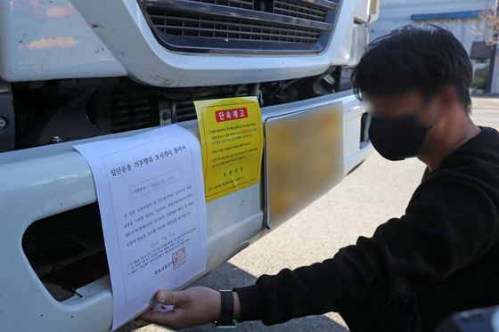 A Pohang city office employee posts a notification related to the investigation and punishment of union truck drivers who refused to comply with the government’s return-to-work order on a truck parked at a steel industrial complex in Pohang on Thursday. The government extended the order to steel and petrochemical truck drivers amid the ongoing strike. [YONHAP]