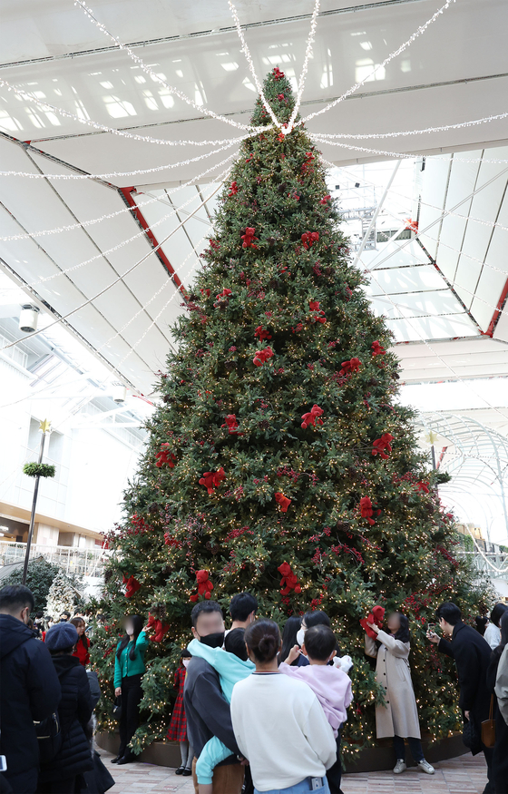 Customers enjoy a huge Christmas tree at The Hyundai Seoul department store in Yeouido on Sunday. [YONHAP]