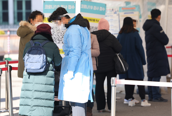 People wait in line to get tested for Covid-19 at a testing center in Seoul Square on Monday. {YONHAP]
