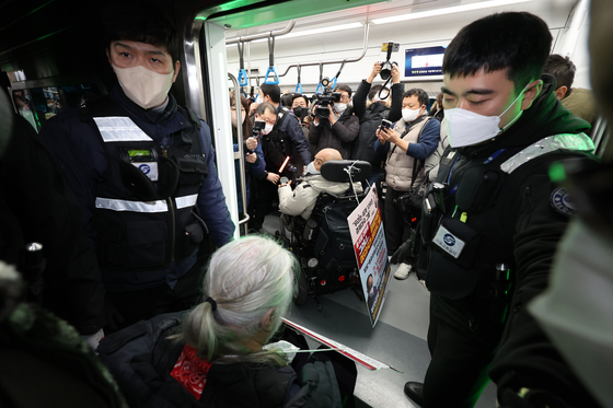 Members of the Solidarity Against Disability Discrimination board a subway train at Samgakji Station in central Seoul on Tuesday as part of a protest demanding more spending on people with disabilities. [YONHAP]