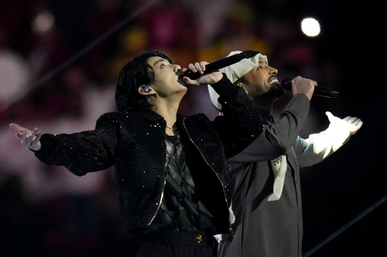 BTS member Jungkook, left, performs with Qatari singer Fahad Al Kubaisi during the opening ceremony of the 2022 Qatar World Cup at Al-Bayt Stadium in Al Khor, Qatar on Sunday. [AP/YONHAP]