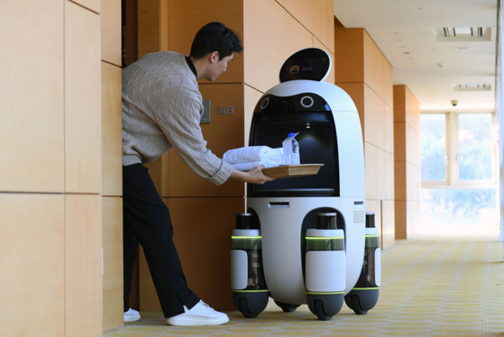 A robot delivers a towel requested via room service to a guest staying at Rolling Hills Hotel [HYUNDAI MOTOR]