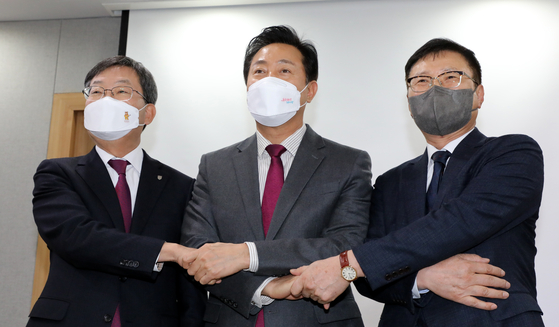 Seoul Mayor Oh Se-hoon, center, poses with Korea University President Chung Jin-taek, left, and Konkuk University President Jeon Young-jae on Monday at City Hall ahead of announcing a set of policies to ease building restrictions on universities in Seoul. [NEWS1]