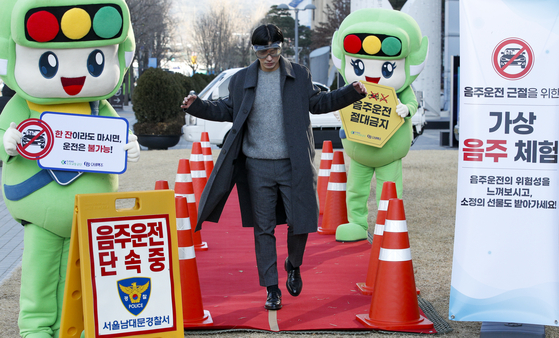 A man tries out a virtual reality (VR) simulation program reenacting what it's like when someone walks around drunk, during a campaign co-held by the Korea Road Traffic Authority and Oriental Brewery on Wednesday near City Hall, central Seoul. [NEWS1]