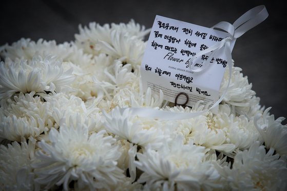 A message of mourning and a bouquet of chrysanthemum flowers are placed at the scene of the Itaewon disaster in central Seoul on Nov. 28, about a month after the crowd crush took the lives of 158 people. [NEWS1]