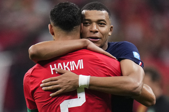 France's Kylian Mbappe hugs Morocco's Achraf Hakimi at the end of the World Cup semifinal match between France and Morocco at the Al Bayt Stadium in Al Khor, Qatar, on Wednesday. France won 2-0 and will play Argentina in Sunday's final. [AP/YONHAP]