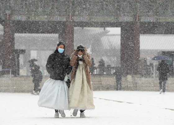 Tourists in hanbok walk in a snowy Gyeongbok Palace in central Seoul on Thursday. [NEWS1] 