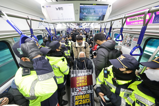 Members of the Solidarity Against Disability Discrimination, including its chief Park Kyoung-seok, hold a protest on a subway train at Yongsan Station in central Seoul on Monday. [YONHAP]
