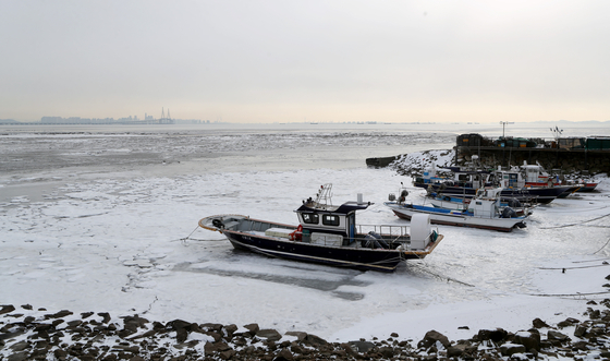 A fishing boat is stranded in a frozen mudflat off Yeongjong Island, Incheon, on Monday. The freezing temperatures continued into Monday with some areas such as Cheorwon, Gangwon, dropping to minus 20 degrees Celsius (minus 4 degrees Fahrenheit). Seoul in the morning dropped to minus 12 degrees Celsius before rising up to minus 3 degrees Celsius during the day. The bitter cold is expected to continue until Tuesday morning while rain or snow is expected on Wednesday. [YONHAP]