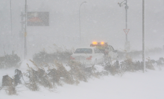 A vehicle is being towed away amid a blizzard in Jeju, Jeju Island, on Dec. 18, 2022. [YONHAP]