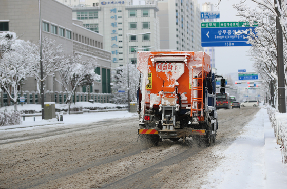 A vehicle sprays salt on the roads in Gwangju on Dec. 18 during a heavy snow advisory. [YONHAP] 