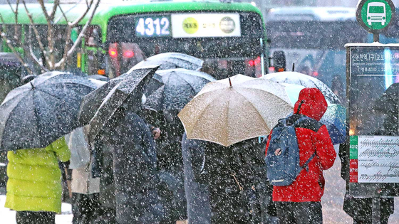 People wait in line at a bus stop at Gangnam Station in southern Seoul on Wednesday morning as heavy snow advisories were issued for the capital area. [NEWS1]