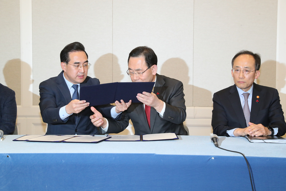 From left, Democratic Party floor leader Park Hong-keun and People Power Party floor leader Joo Ho-young exchanges the agreements made on next year's budget as well as other pending issues at the National Assembly in Yeouido, Thursday next to Finance Minister Choo Kyung-ho. [NEWS1]