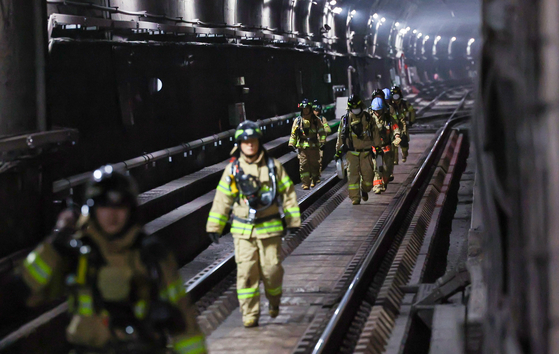 Fire fighters exit Muakje Station's underground railways after extinguishing a fire that broke out at the station on Friday. [YONHAP]