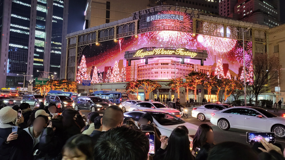 A crowd of people taking photos of the Shinsegae Department Store's facade on the evening of Dec. 9 in central Seoul. [CHOI SEO-IN] 