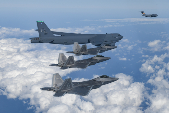 A U.S. B-52 Stratofortress bomber flies alongside three F-22 Raptor stealth bombers and a C-17 Globemaster transport aircraft in the distance during a training mission near the Korean Peninsula on Dec. 20. [DEFENSE MINISTRY]