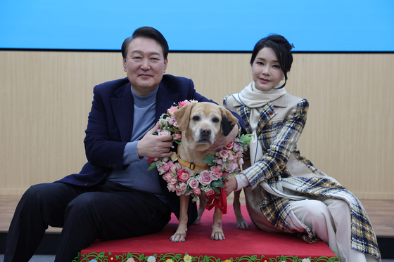 President Yoon Suk-yeol, left, and first lady Kim Keon-hee invite the newest member of the presidential family Saeromi, a retired guide dog, after adopting her from the Samsung Guide Dog School in Yongin, Gyeonggi, on Saturday. [PRESIDENTIAL OFFICE]