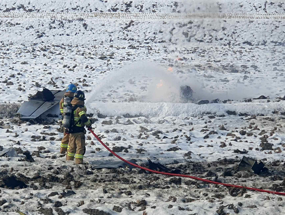 Firefighters pour water onto the site of a warplane crash in Hoengseong County, about 140 kilometers (87 miles) east of Seoul, on Dec. 26. [YONHAP]