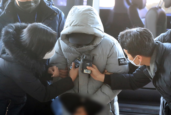 The suspect on charges of murdering a woman who owns a famous restaurant in Jeju is questioned by reporters as he is sent to the Jeju Dongbu Police Precinct on Dec. 20. [YONHAP] 