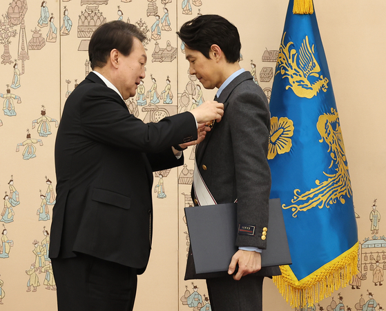 President Yoon Suk-yeol, left, confers the Geumgwan Order of Cultural Merit to Squid Game actor Lee Jung-jae Tuesday. [JOINT PRESS CORPS]