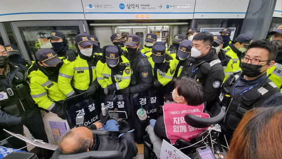 Members of the Solidarity Against Disability Discrimination (SADD) are blocked by the police at Samgakji Station in central Seoul on Monday. [SOLIDARITY AGAINST DISABILITY DISCRIMINATION]
