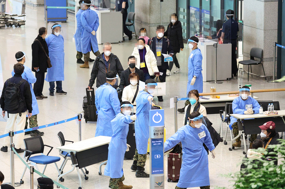 Health officials guide travelers from China to a Covid-19 testing site at Incheon International Airport on Tuesday. [YONHAP]