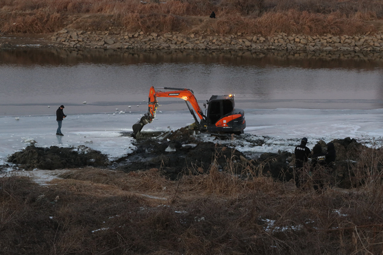 Police search Gongneung stream in Paju for the remains of a woman on Tuesday. Lee Ki-young, who is accused of murdering a taxi driver in December, allegedly confessed to murdering his girlfriend last August. Lee is expected to appear in public on Wednesday for the first time since the police disclosed his identity on Dec. 30. [YONHAP]