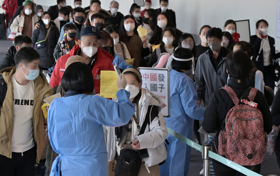 Quarantine officials help travelers from China get compulsory PCR tests for the coronavirus on Monday at Incheon International Airport. [YONHAP]