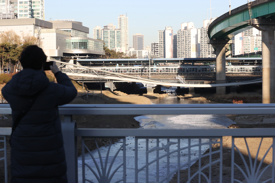 A passer-byer takes a picture of the slumped walkway that connects Sindorim subway station with Dorim-dong in Yeongdeungpo District, western Seoul, that dipped in the middle on Tuesday. The police said it received a report that the walkway, which was built six years ago, slumped down at 1 a.m. in the morning. Entrance was entirely banned from both entries, as well as access to the bicycle road that runs underneath the bridge. The bridge is 104.6 meters (343 feet) long and 2.5 meters wide. While no injuries have been reported, some of the supporting cement and the guardrail have been damaged. [YONHAP]