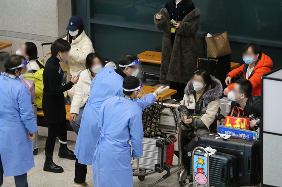 Health officials explain to Chinese travelers the mandatory PCR test for the coronavirus on Wednesday at Incheon International Airport, a day before restrictions on Chinese arrivals get even stronger. [NEWS1]