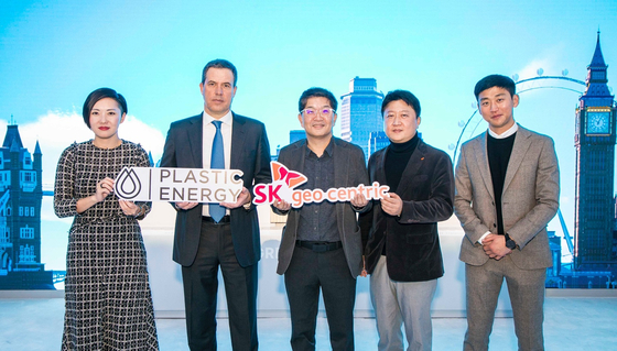 SK geo centric CEO Na Kyung-soo, center, and Bruno Guillon, chief commercial officer of Plastic Energy, second from left, take a photo at SK booth for the CES 2023 show. [SK GEO CENTRIC]  